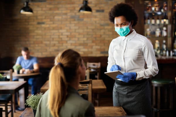 Masked server taking order in a restaurant