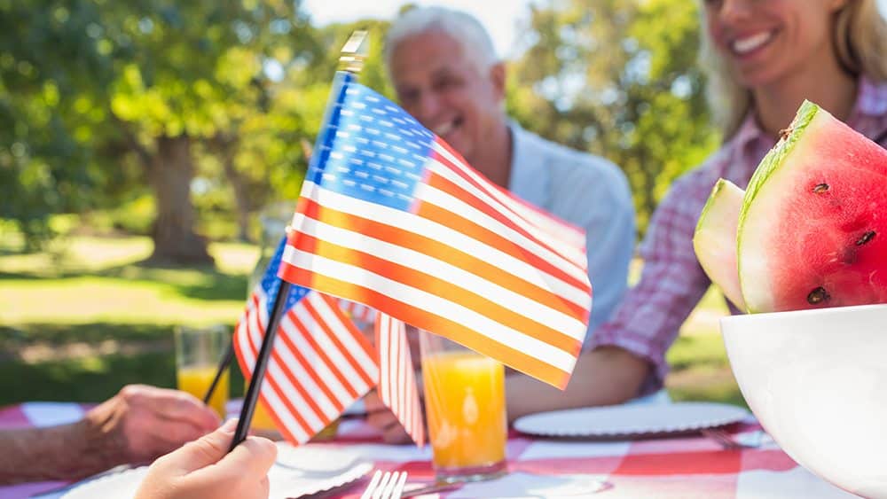 Happy family having picnic and holding american flag